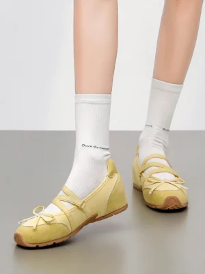 Pale yellow bow Mary Jane ballet flats worn with printed white crew socks in top-down outfit view