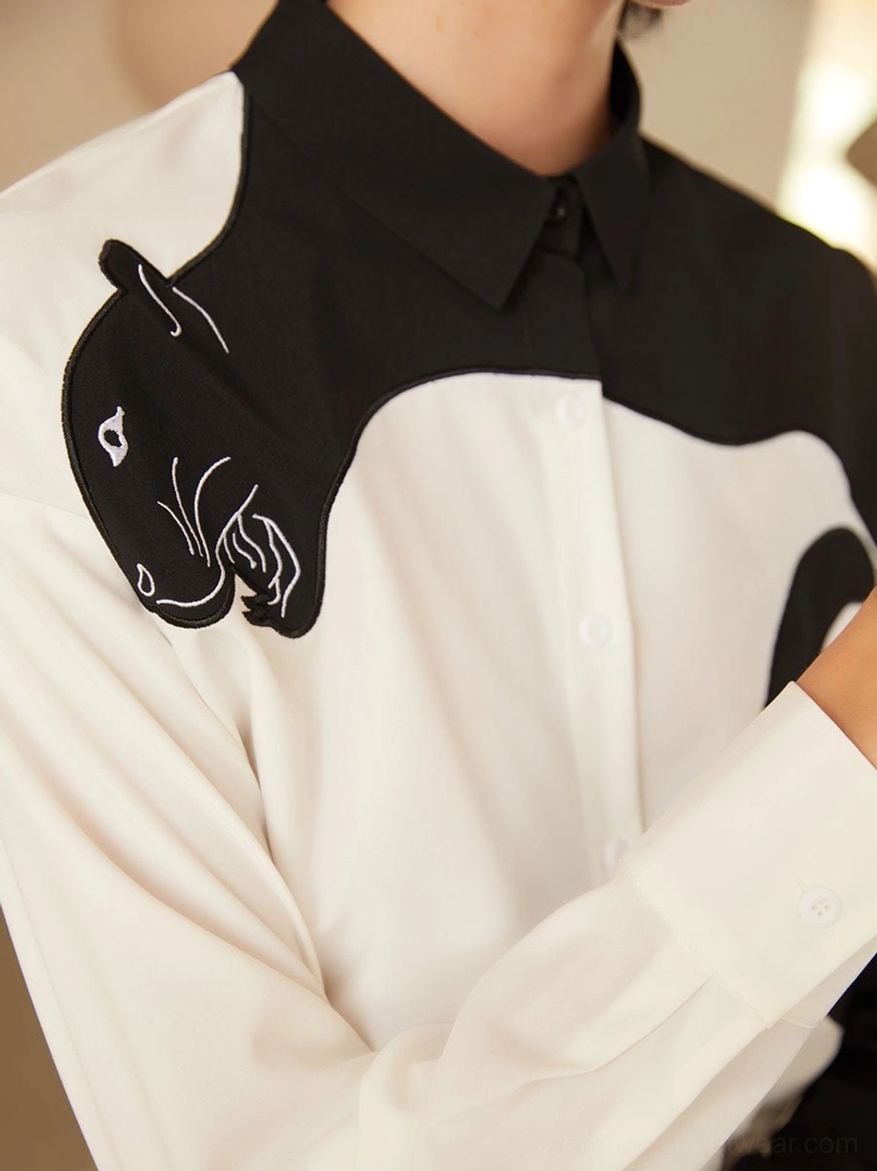 Close-up of panther embroidery, classic shirt collar, button placket, and black white color block blouse details
