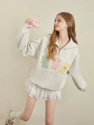 Three quarter view of Korean style grey quarter zip streetwear sweatshirt with pastel bear appliques and relaxed oversized fit