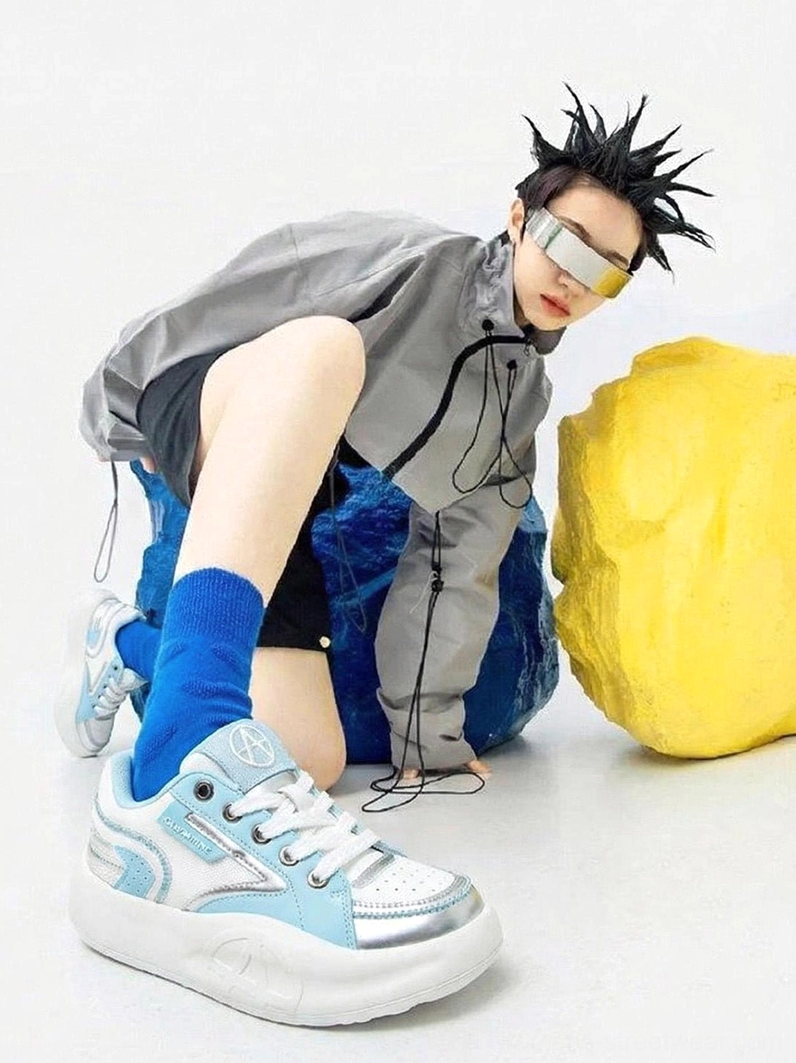 Pastel breathable runner sneakers worn with a gray windbreaker black shorts and blue socks in a futuristic streetwear look