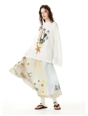 Side view of a Korean streetwear pastel cat print maxi skirt styled with a graphic long sleeve top, leg warmers, and brown sandals