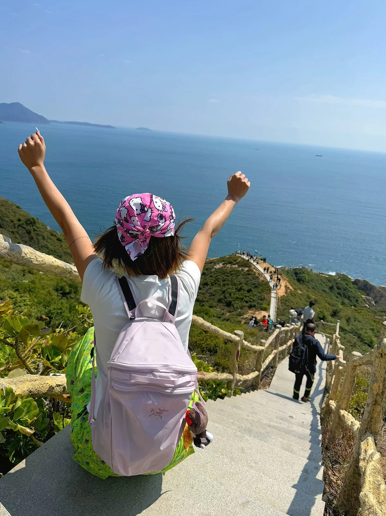 Back view of pastel meadow floral fitted tee styled with wide-leg pants on a coastal mountain stairway