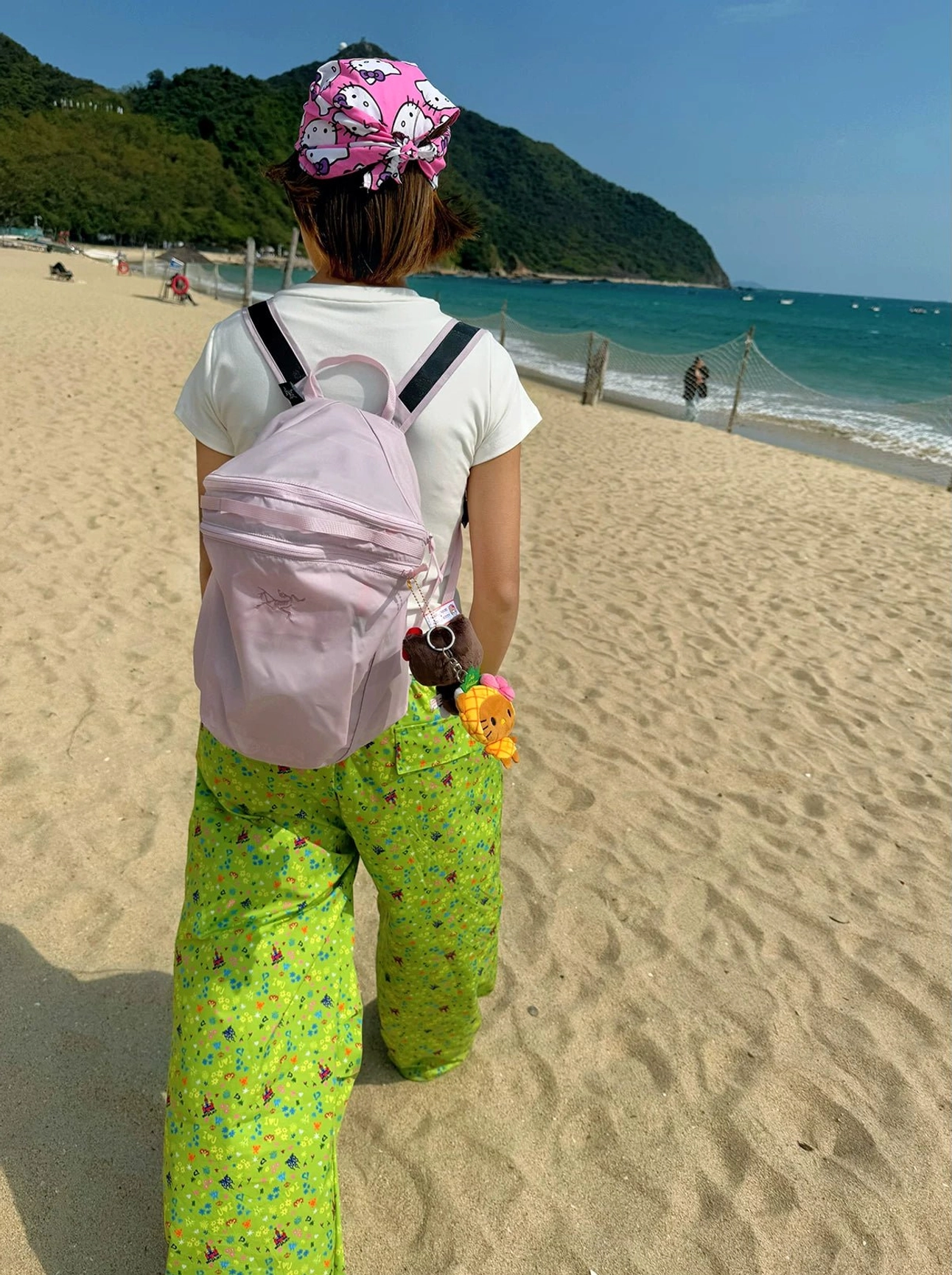 Cream floral fitted baby tee styled in a relaxed beach streetwear outfit by the ocean shoreline