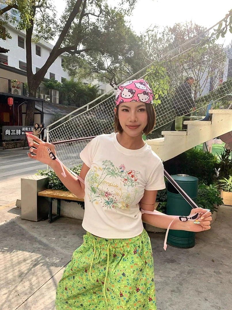 Front view of creamy white pastel meadow floral fitted baby tee with cropped slim streetwear silhouette