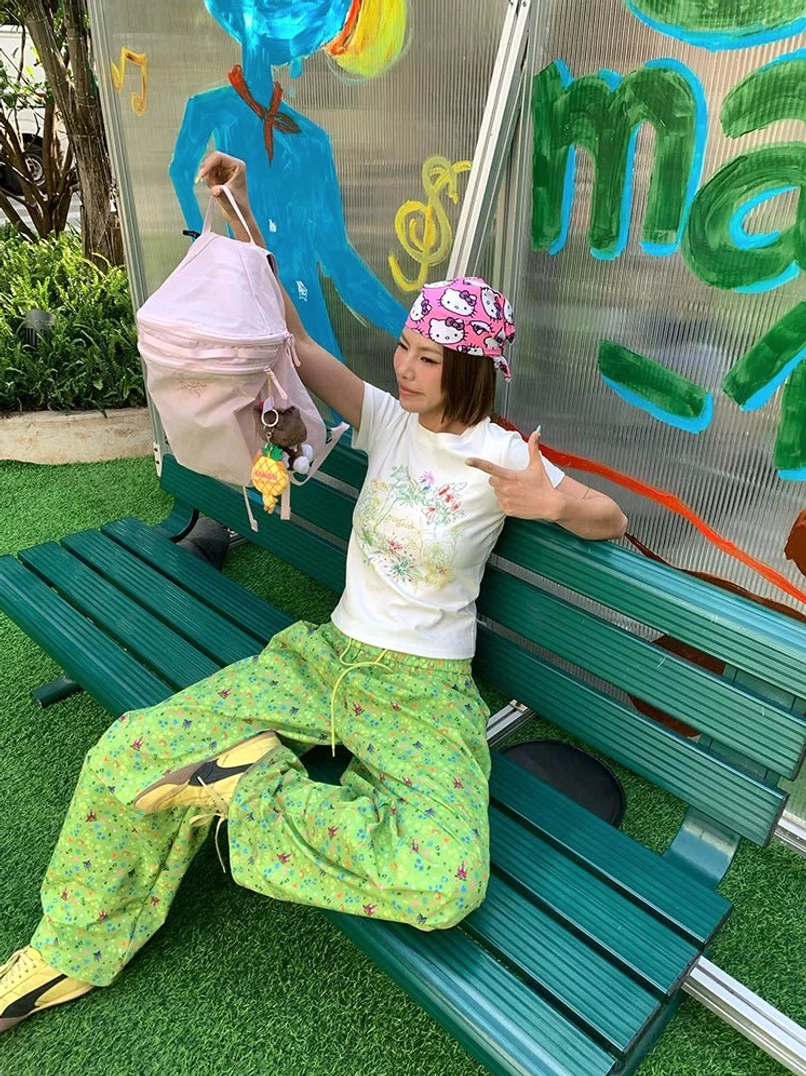 Pastel floral fitted baby tee with green printed wide-leg pants in front of an urban graffiti wall