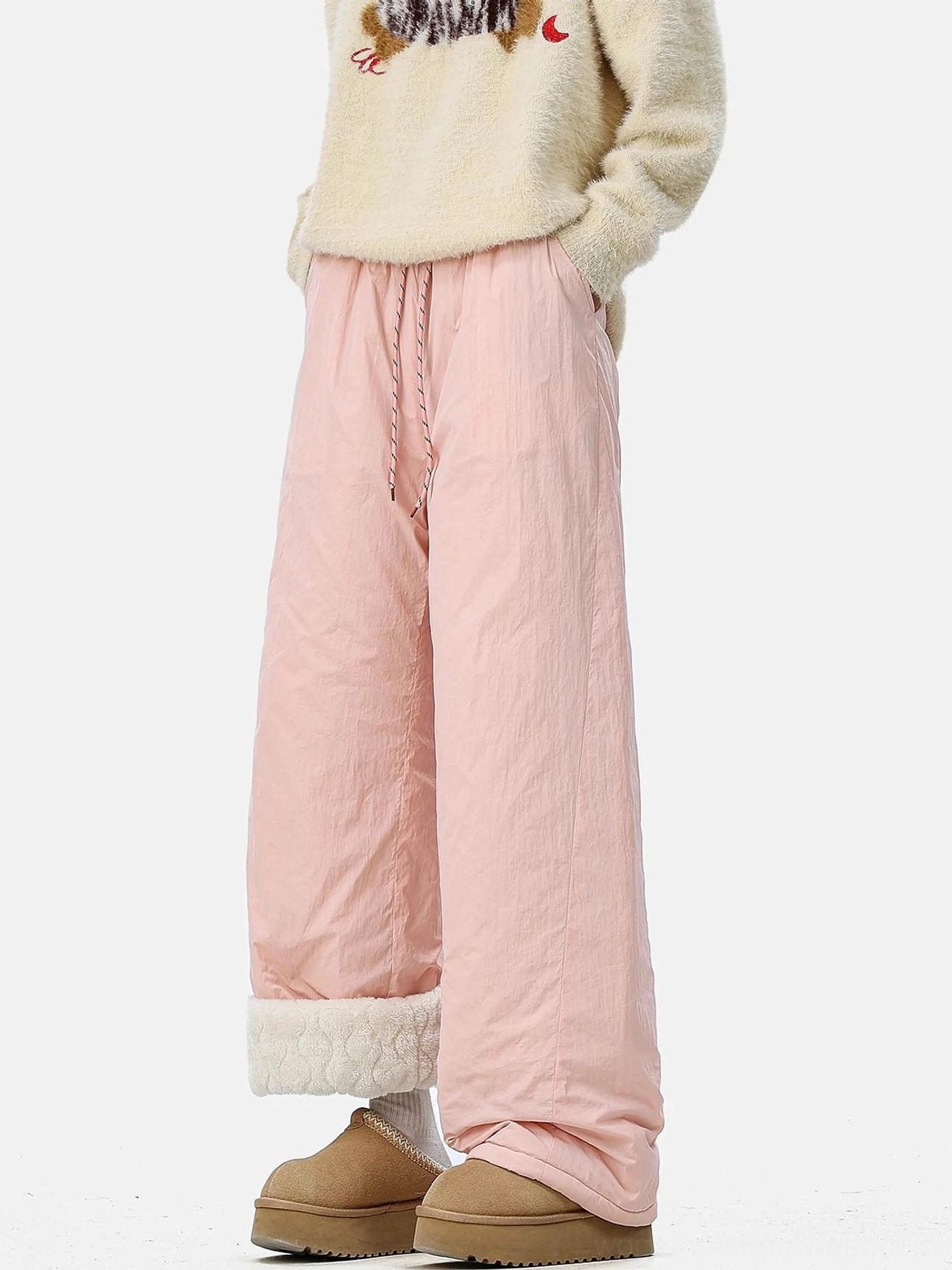 Pastel pink convertible wide-leg streetwear pants with rolled fleece cuffs, elastic drawstring waist, fuzzy sweater, and snow boots