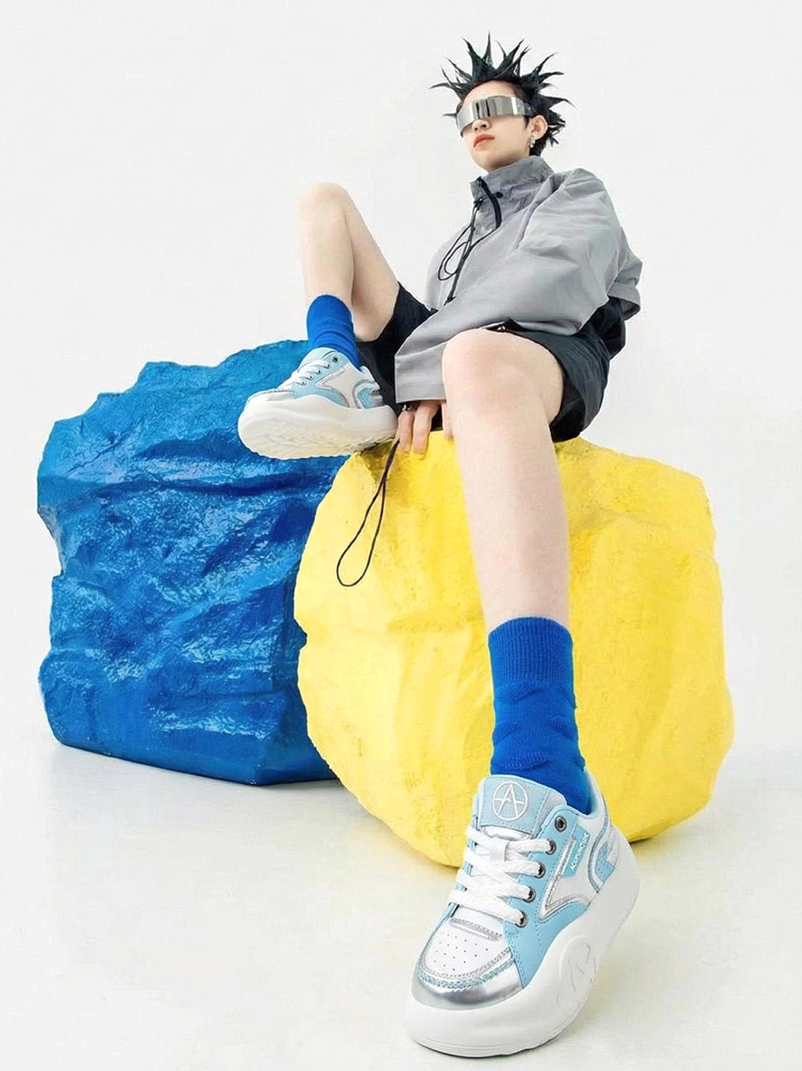 Pastel platform sneakers worn with blue socks and casual streetwear styling in a colorful studio fashion scene