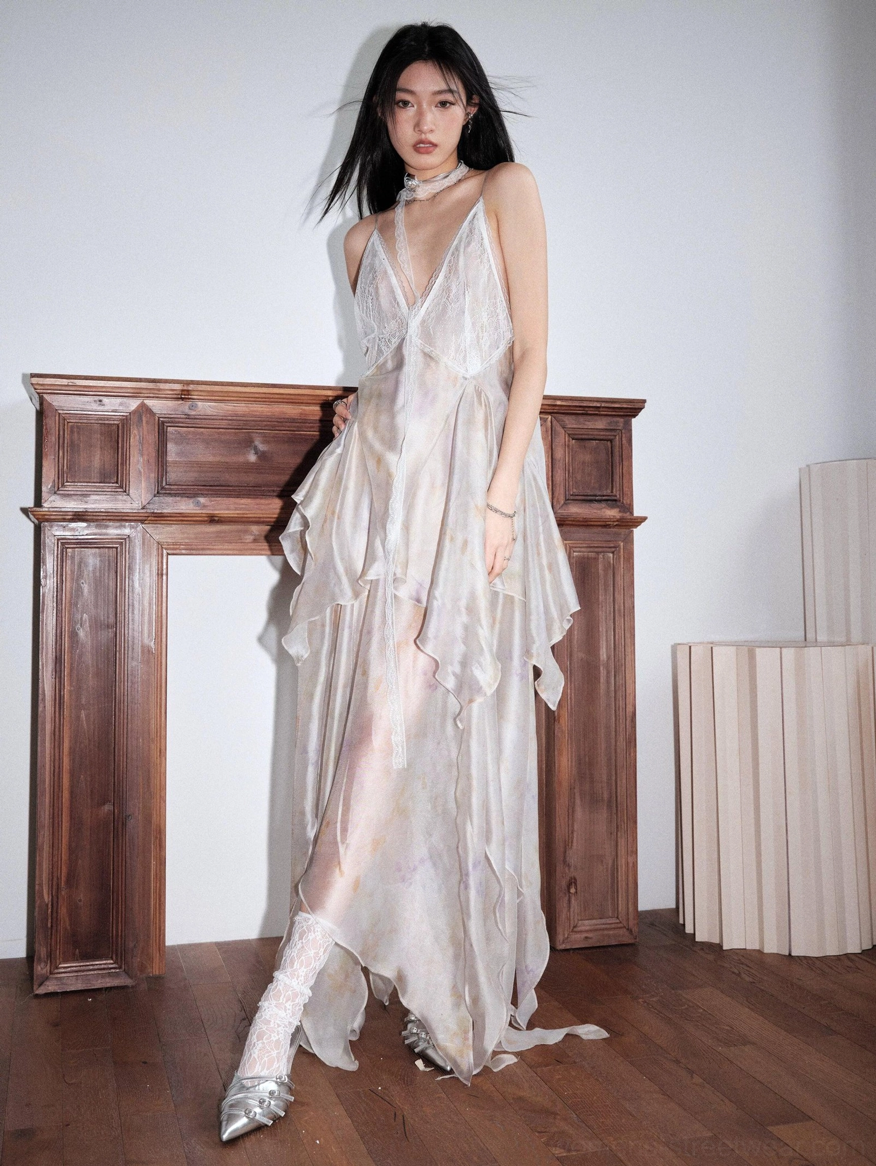 Pastel tie dye chiffon maxi slip dress shown from the back three-quarter view with open back, sheer flowing layers, uneven floor-length hem, and silver ankle boots