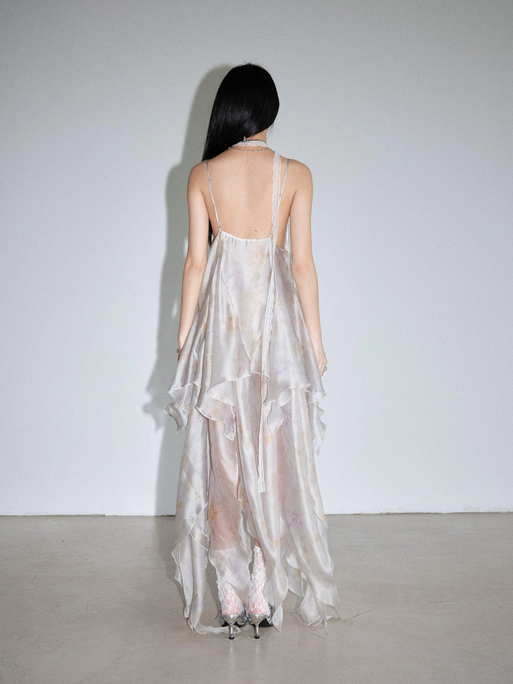 Pastel tie dye chiffon slip dress shown from the back with single spaghetti strap detail, open back design, and asymmetric layered maxi skirt