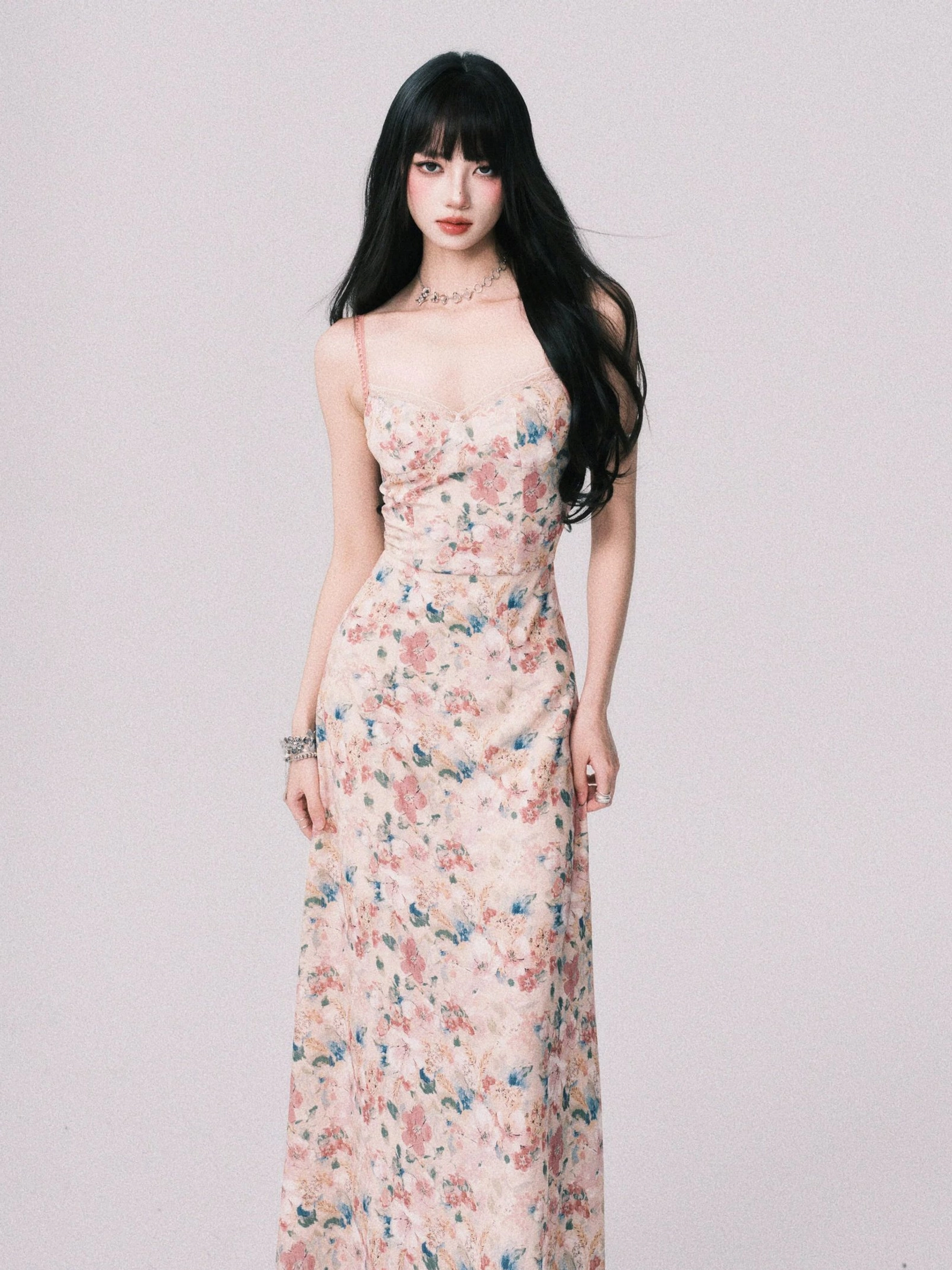 Front full body view of a pastel watercolor floral cami maxi dress with ruched bust, fitted waist, slim spaghetti straps, and flowing ankle length skirt
