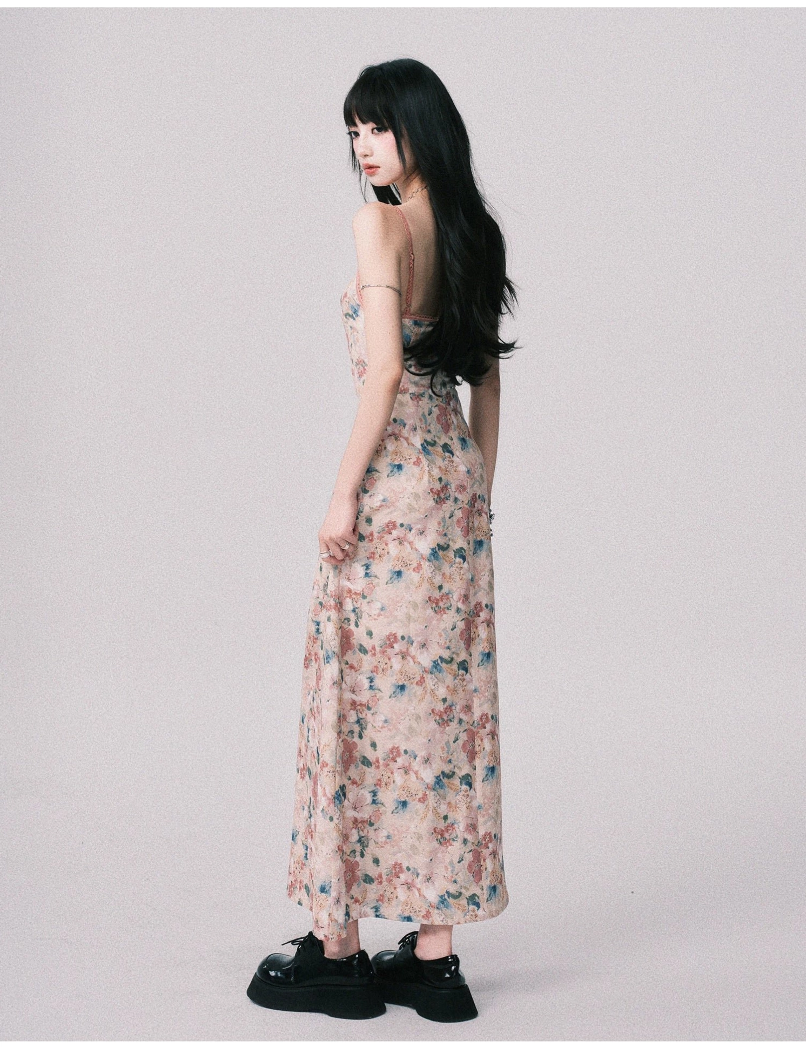Side back view of a backless floral maxi dress with slim spaghetti straps, open back silhouette, and floor length watercolor printed skirt
