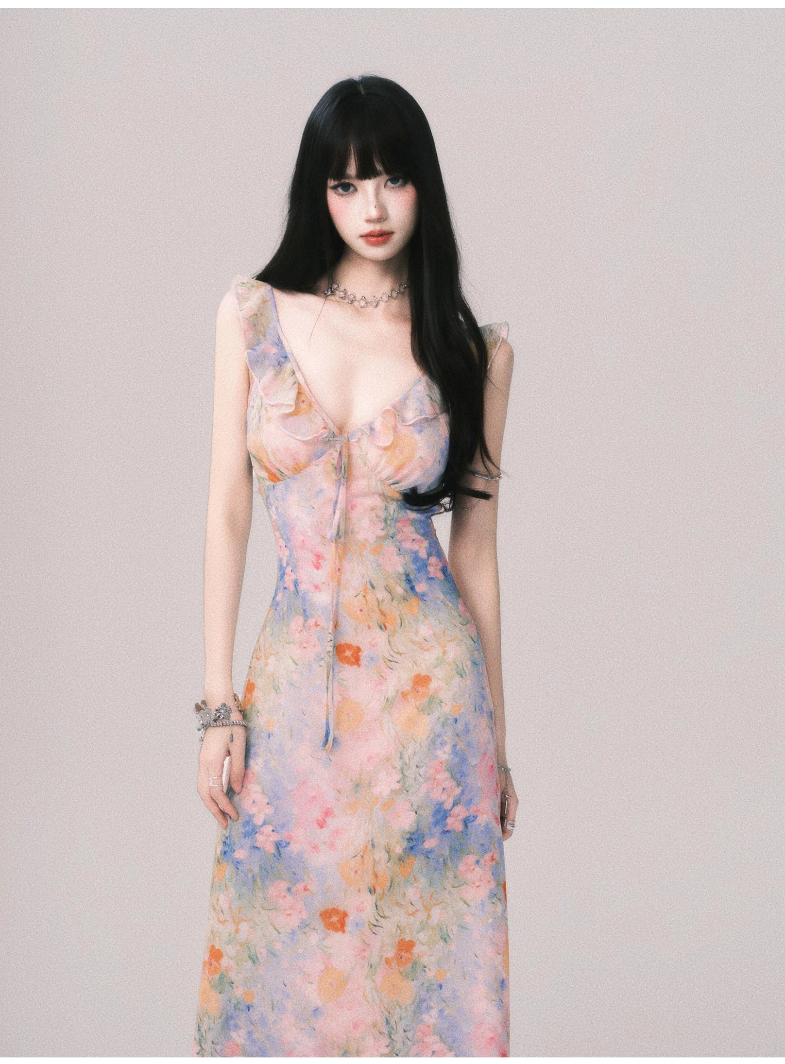 Close-up of the deep V neckline, delicate ruffle trim, and pastel watercolor floral fabric on women's maxi slip dress