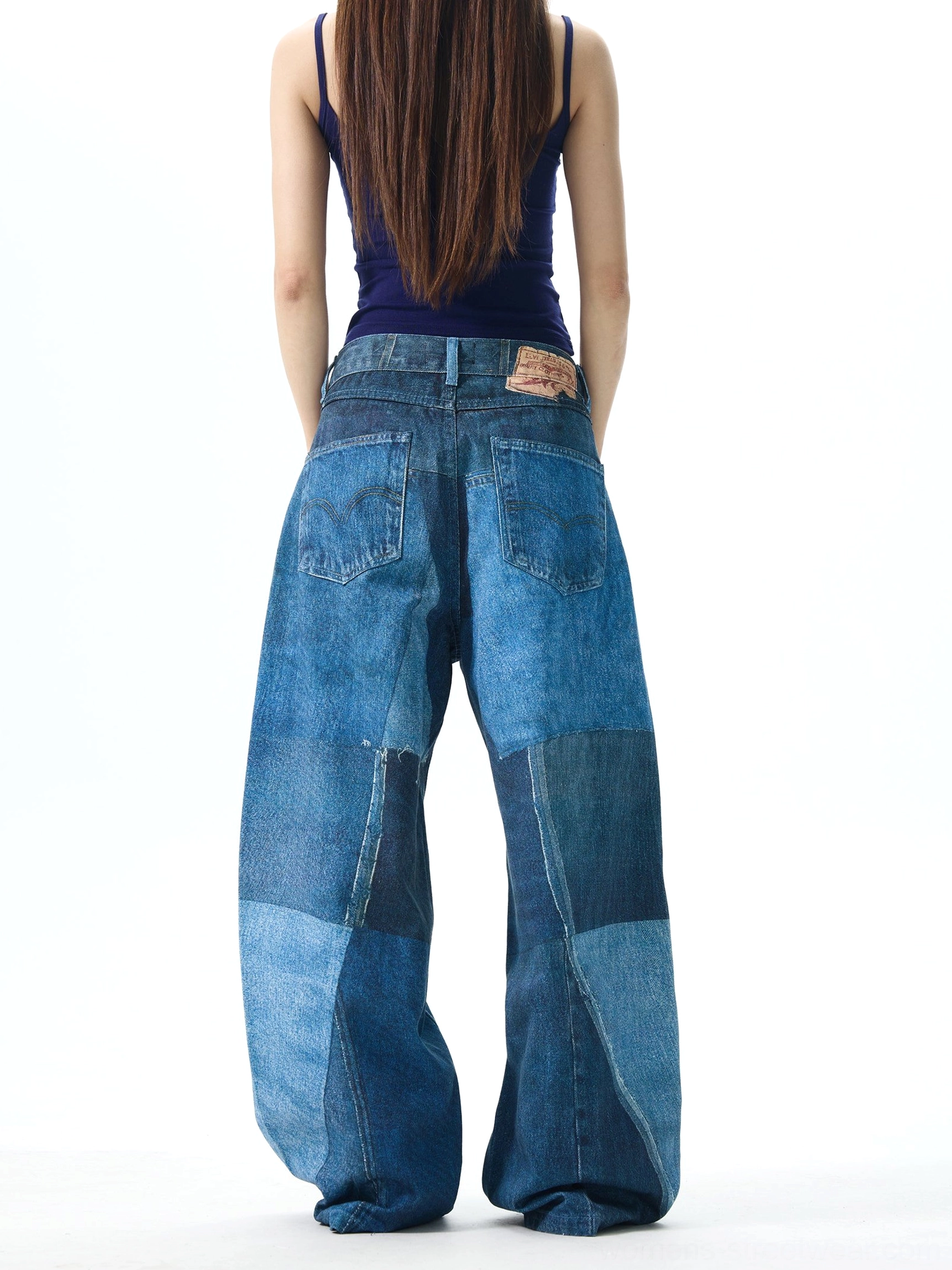 Back view of women's patchwork wide leg jeans showing double rear pockets, full panel indigo denim construction, leather waist patch, and loose fit