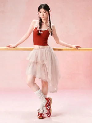 Model wearing red pearl lace ballet runner sneakers with a red balletcore outfit in a pink dance studio