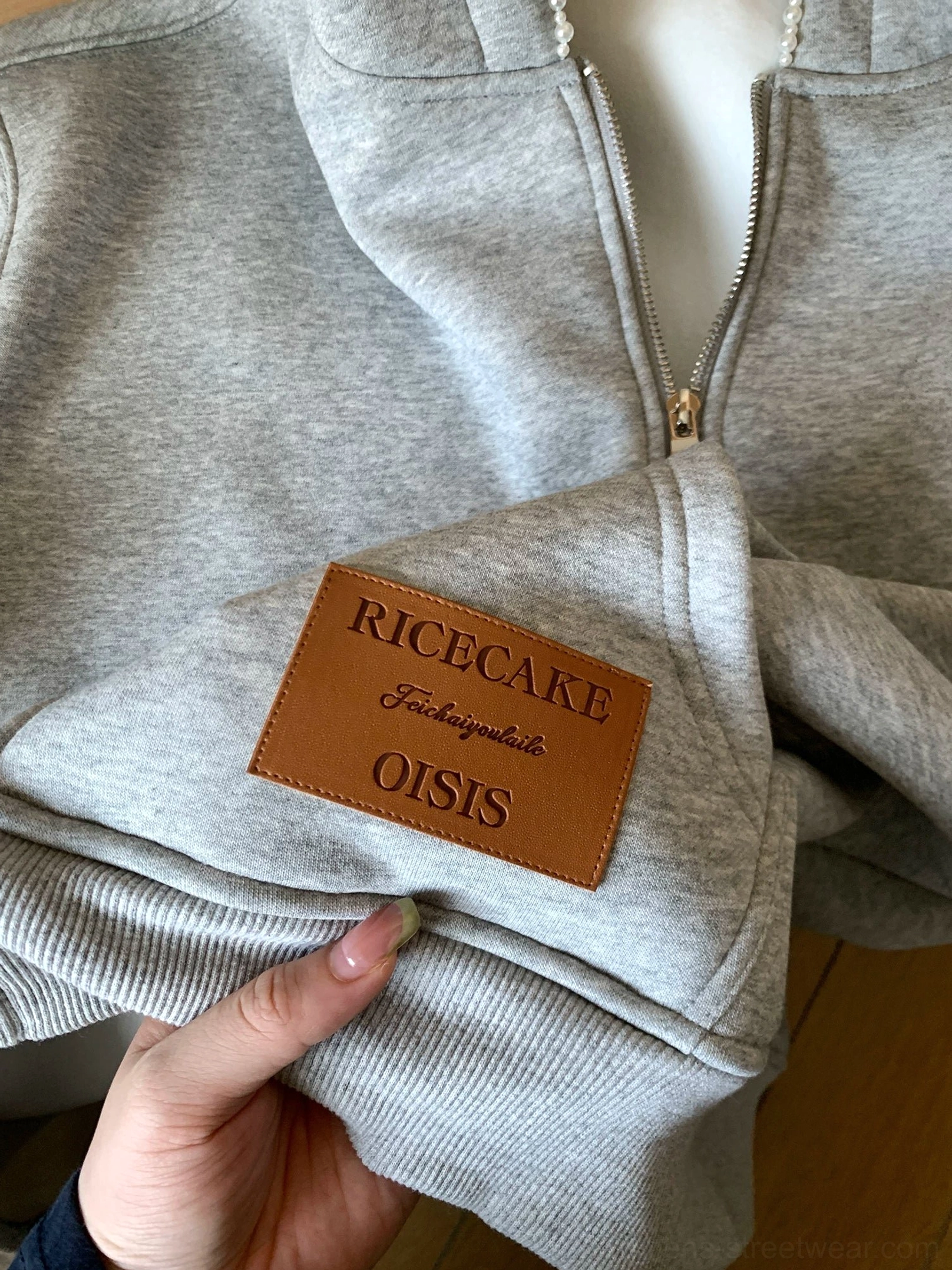 Close-up of heather gray oversized zip-up cloud hoodie showing metal zipper heavyweight fleece and hem patch