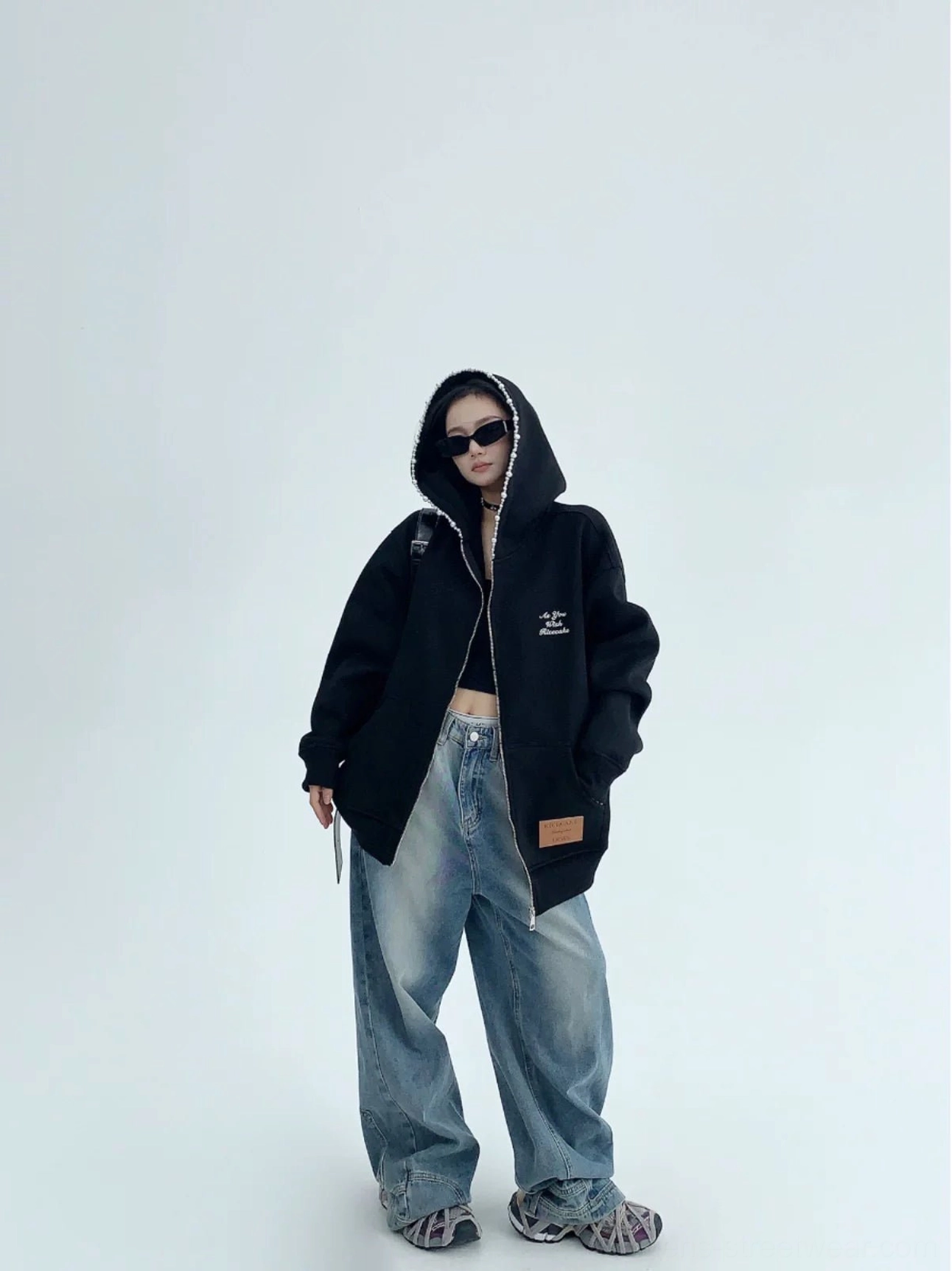 Black oversized pearl trim zip-up hoodie for women paired with wide-leg jeans and chunky sneakers