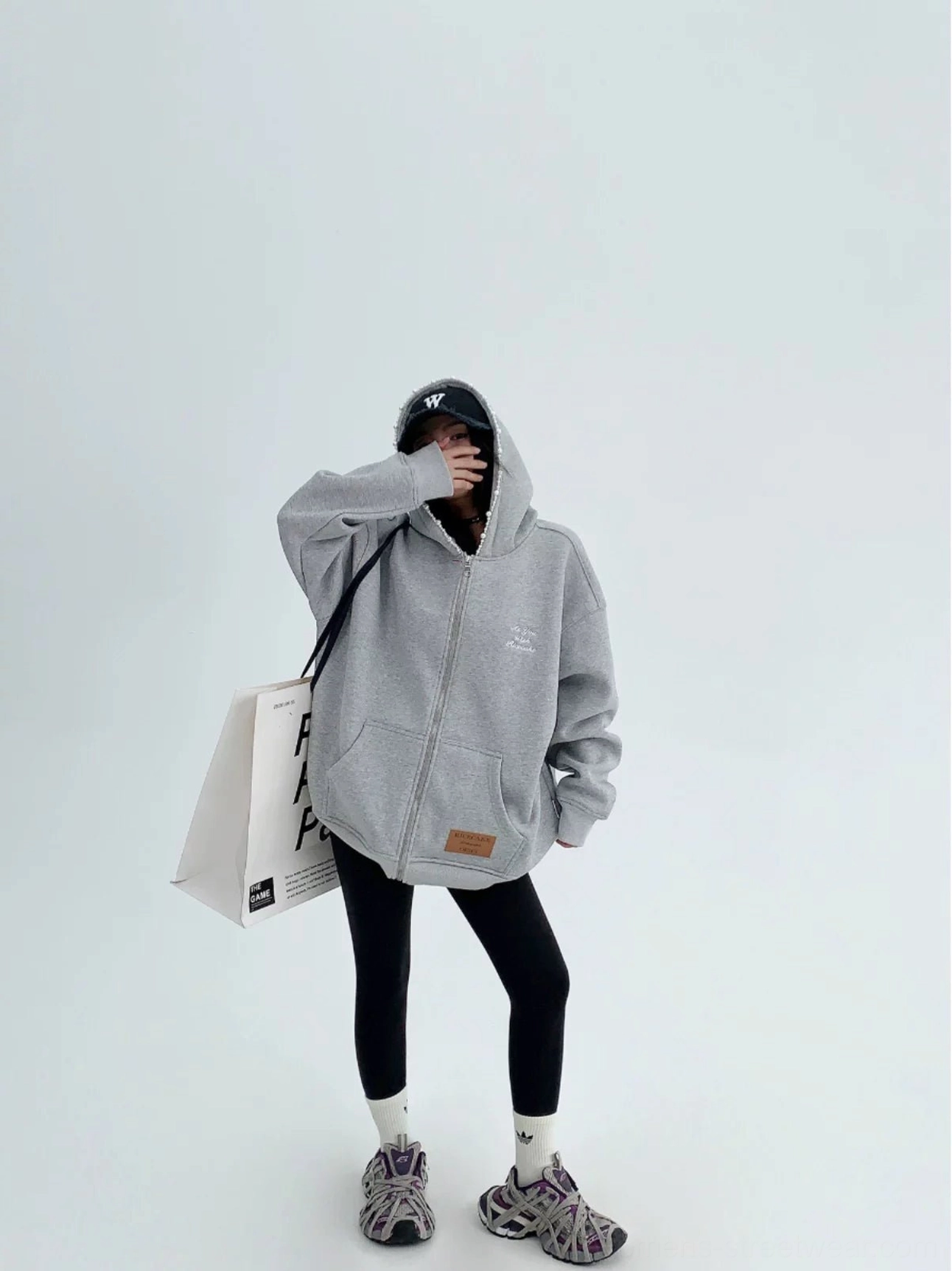 Heather gray oversized pearl trim zip-up hoodie for women styled with black cap leggings and chunky sneakers