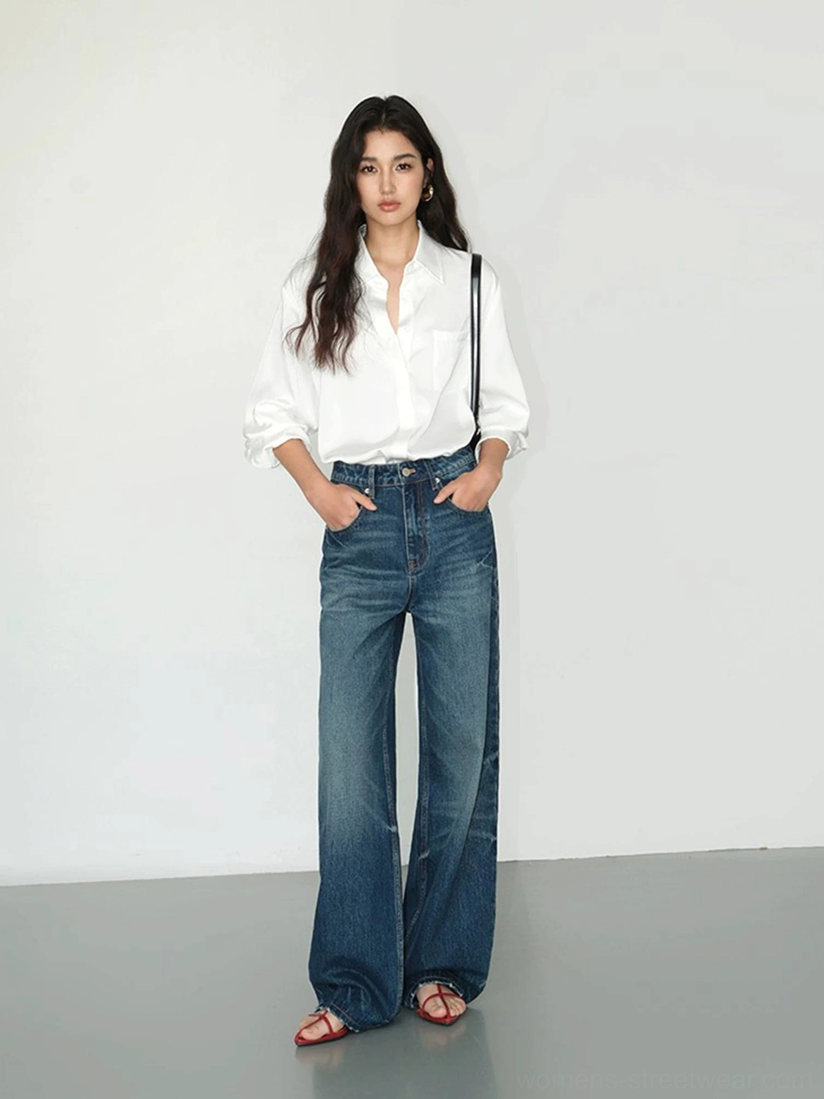 Full body view of a pearl white satin draped pocket shirt with wide leg jeans and sandals in a minimalist outfit