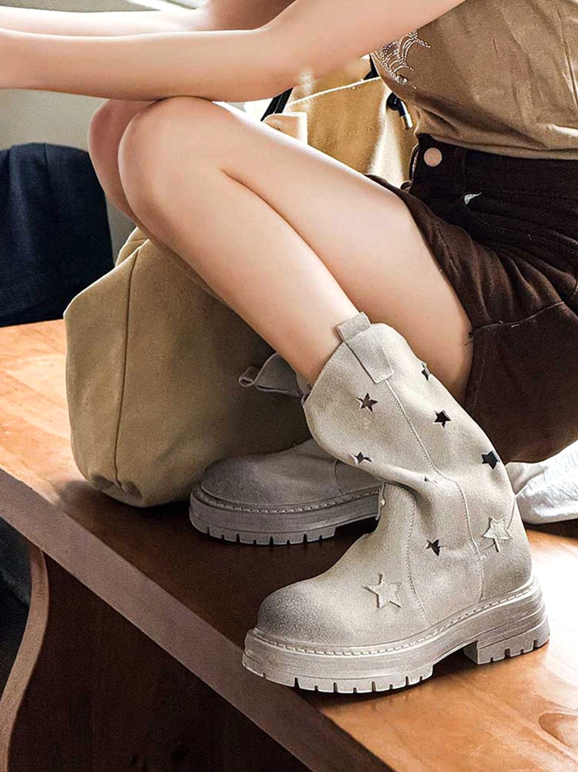 Star-decorated platform mid-calf boots overhead side view worn with casual streetwear outfit on wooden table setting with model styling