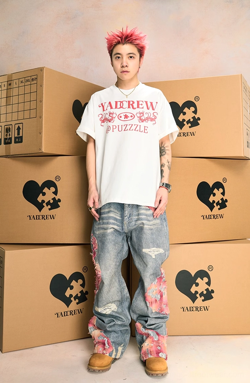 Full front streetwear outfit featuring pink-accented distressed wide-leg jeans, oversized white graphic tee, pink hair, and tan work boots