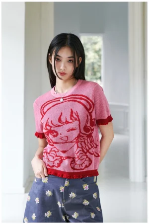 Pink anime jacquard cropped knit top with red ruffle trim styled with floral print pants in a bright indoor corridor