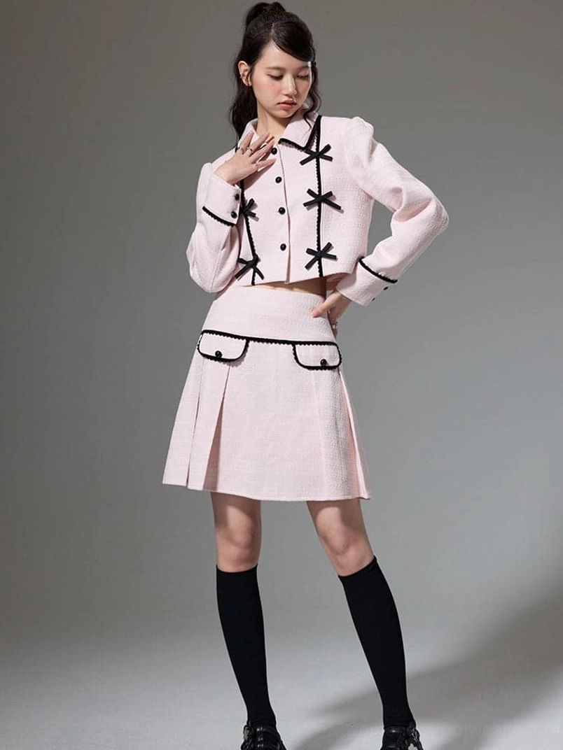 Full body view of pink cropped jacket and pleated mini skirt styled with black knee high socks