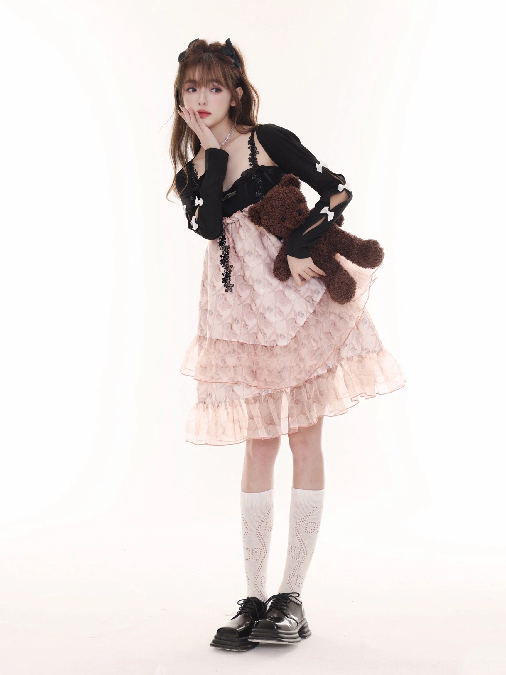 Side view of pink floral layered cake dress with black cropped cardigan white socks and loafers