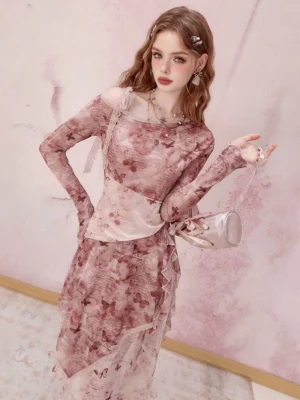 Three quarter front view of a pink floral long sleeve midi dress with an off shoulder neckline, fitted bodice, layered ruffle hem, and handbag