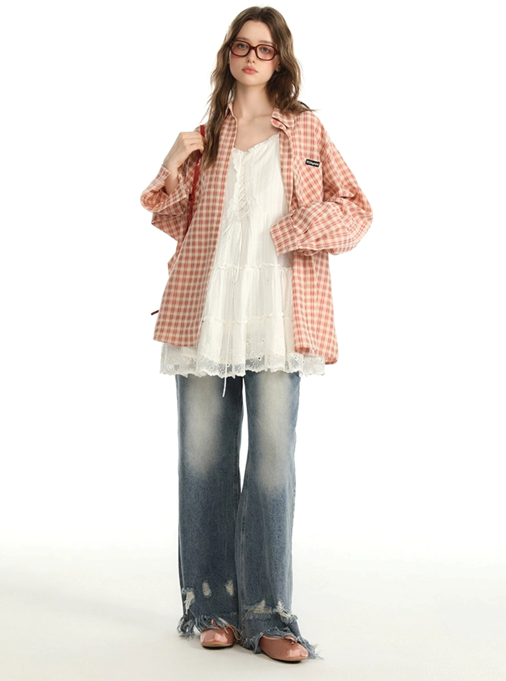 Front view of a pink gingham long-sleeve shirt with relaxed shoulders worn open over a white lace inner dress