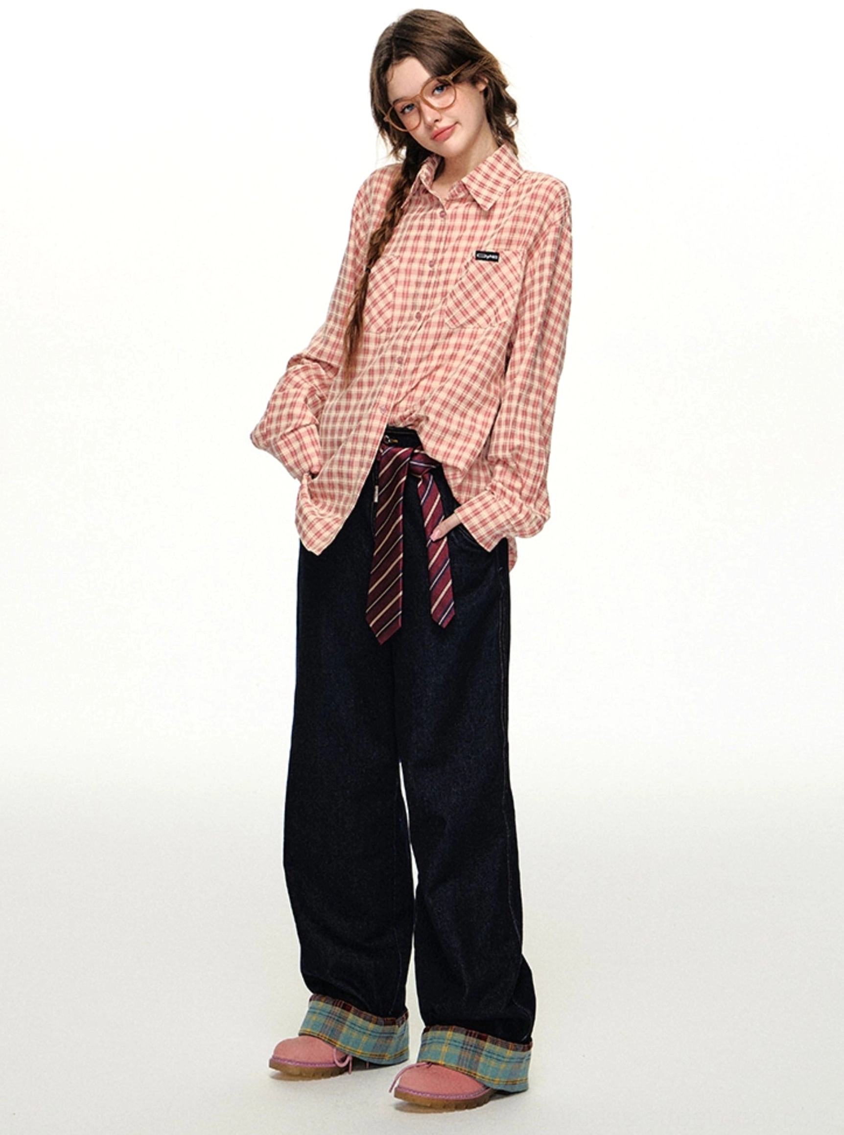 Front three-quarter view of a relaxed pink gingham button-down shirt with chest pocket and wide-leg streetwear trousers
