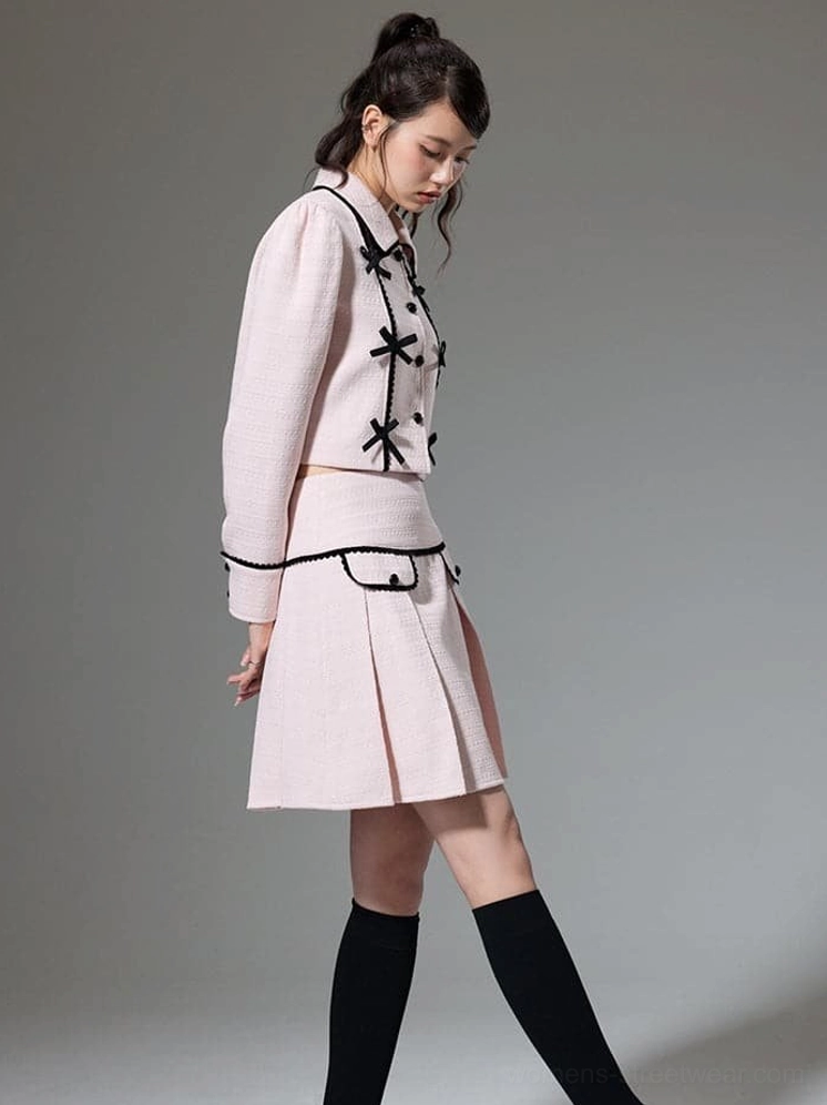 Side view of pink high waist pleated mini skirt with black braid trimmed pockets and cropped jacket