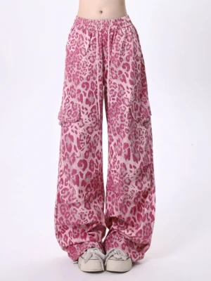 Front view of pink leopard print wide leg cargo pants with elastic drawstring waist oversized flap pockets and relaxed streetwear silhouette styled with beige sneakers