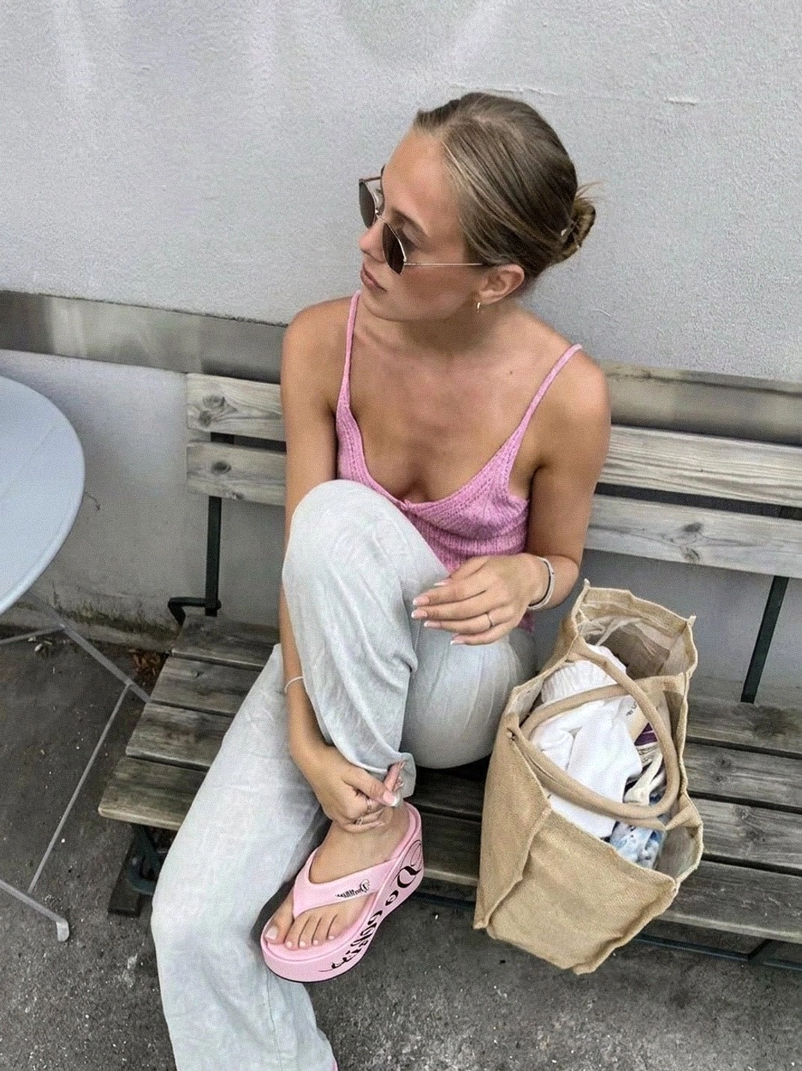 Pink logo print 10cm platform wedge flip-flops worn with a pink camisole and wide leg trousers