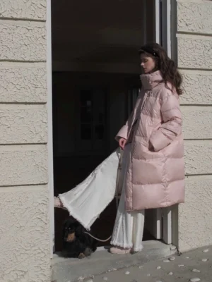 Pink longline puffer coat with oversized stand collar and side pockets styled at a villa doorway