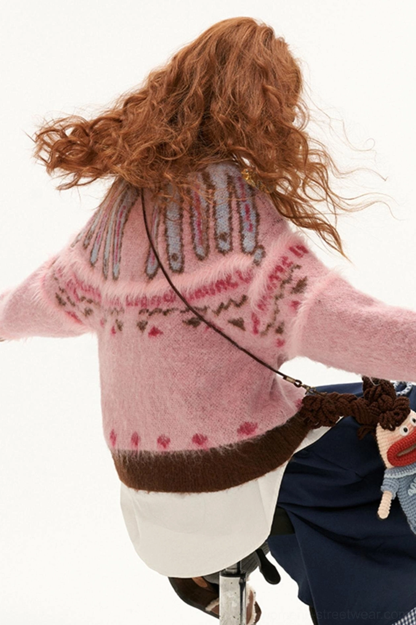 Dynamic back view of pink fuzzy mohair Fair Isle cardigan with brown hem trim and heart knit pattern