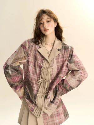 Close-up front view of a pink plaid oversized blazer with beige contrast lapels, pleated tie-front details and matching pleated mini skirt