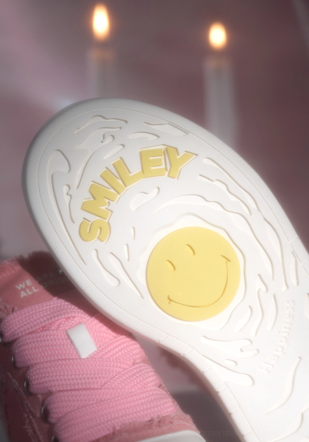Close-up view of pink platform skate sneaker insole with raised yellow smiley-face logo, embossed lettering, and wavy textured white footbed