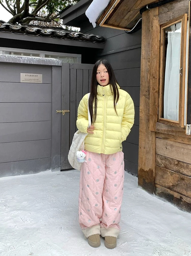 Pink polka dot quilted fleece cuff pants styled with a yellow puffer jacket for a colorful winter streetwear outfit