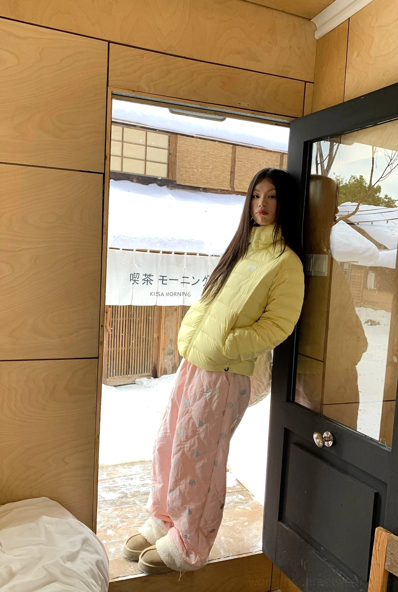 Side view of pink polka dot quilted wide leg pants with plush fleece cuffs styled in a winter doorway