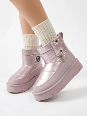 Low angle view of pink quilted platform snow boots on model wearing cream crew socks featuring circular ankle badge side zipper closure quilted texture