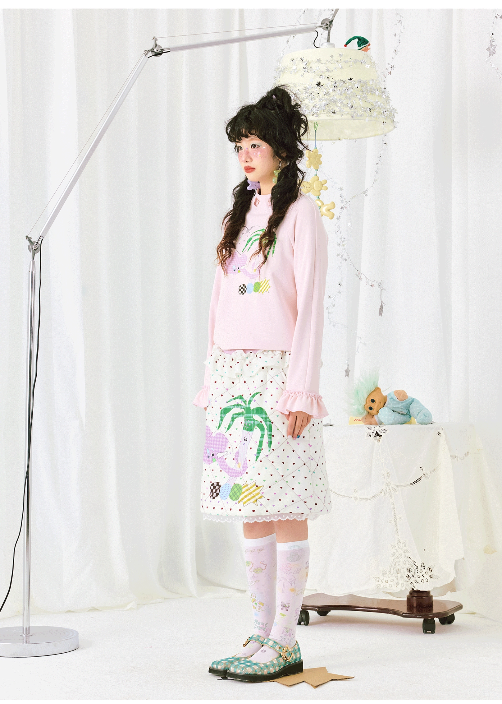 Side view of a Korean-inspired pink ruffle sleeve top with playful palm print styled with knee-high socks and Mary Jane shoes
