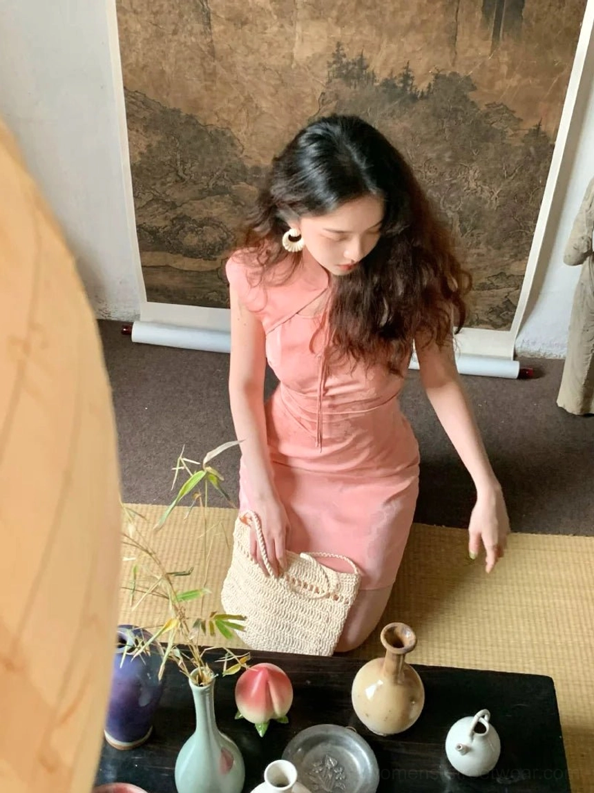 Pink satin cheongsam mini dress with stand collar, fitted waist, mini hem, and elegant woven handbag styling in a traditional tea room
