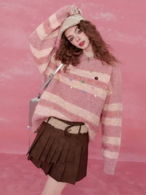 Pink striped fuzzy knit sweater with colorful buttons styled with a brown pleated mini skirt in a pink studio
