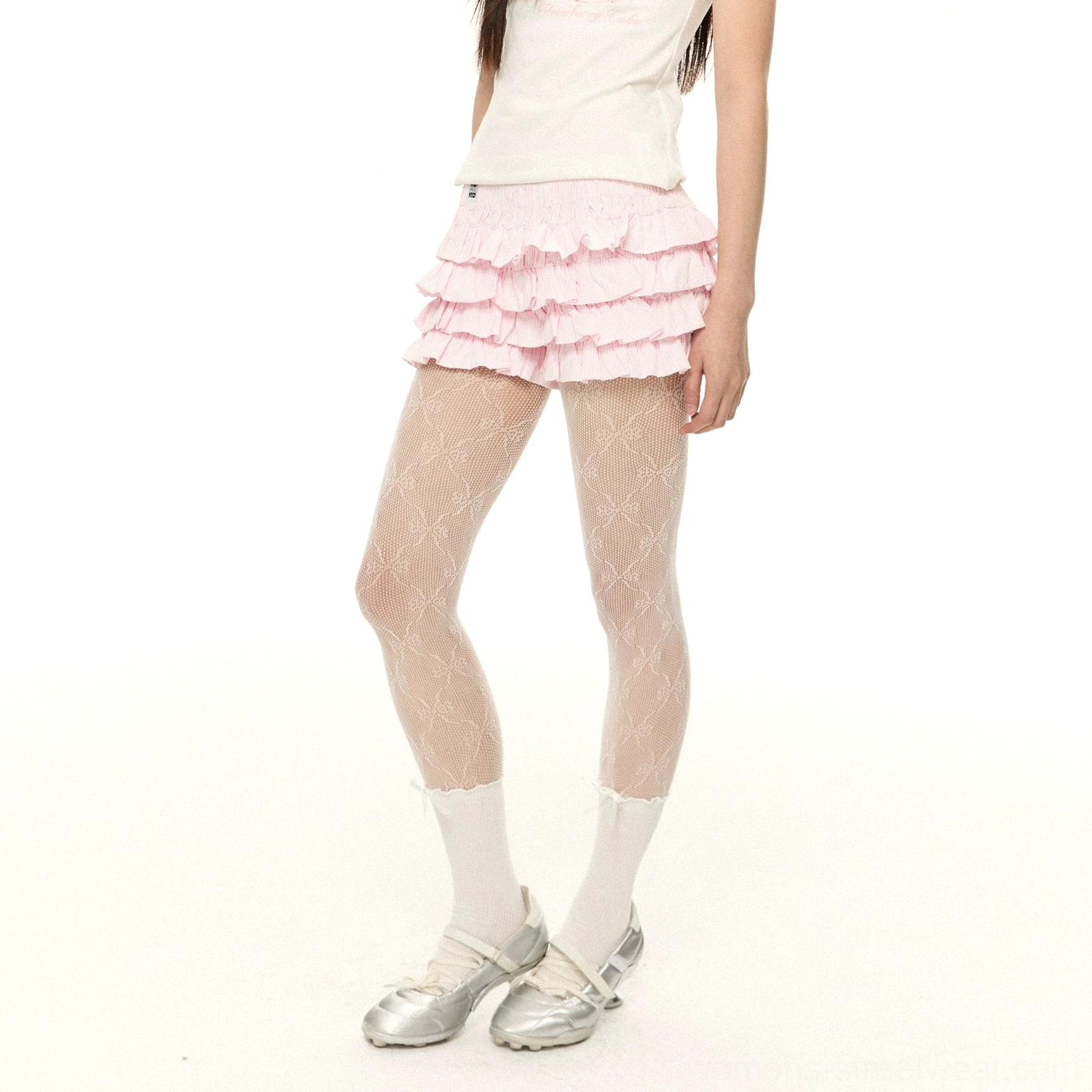 Pink tiered ruffle mini shorts styled with a basic short sleeve tee, floral fishnet tights, white socks, and silver loafers in a feminine streetwear look