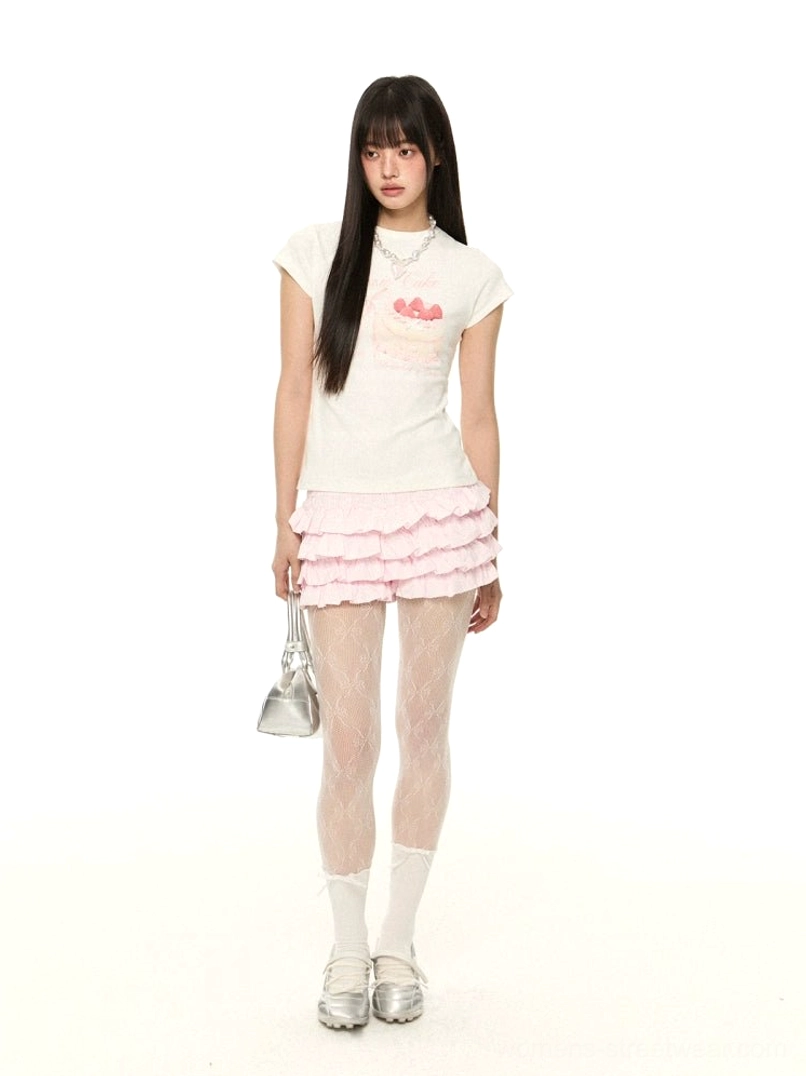 Pink tiered ruffle mini shorts styled with a cake print short sleeve tee, fishnet tights, white socks, silver loafers, and a silver handbag in a full front streetwear outfit
