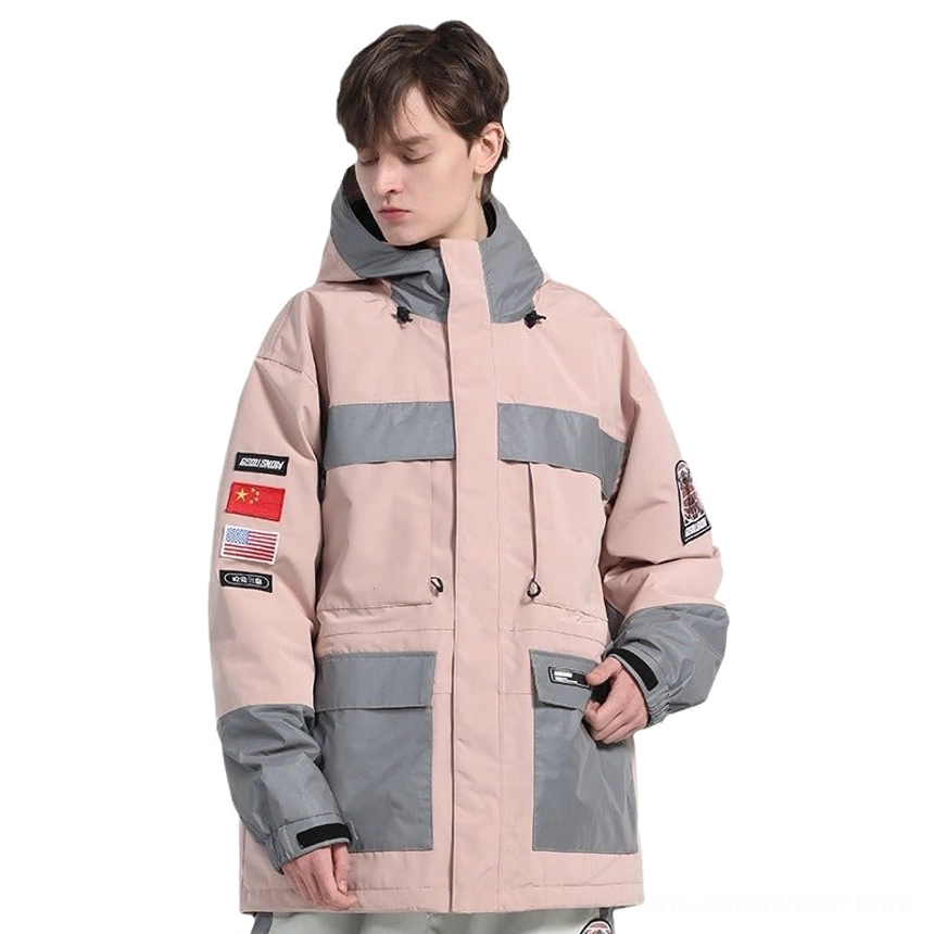 Pink unisex reflective panel ski jacket front three-quarter view showing grey color-block panels, sleeve badges, flap cargo pockets, and adjustable hood