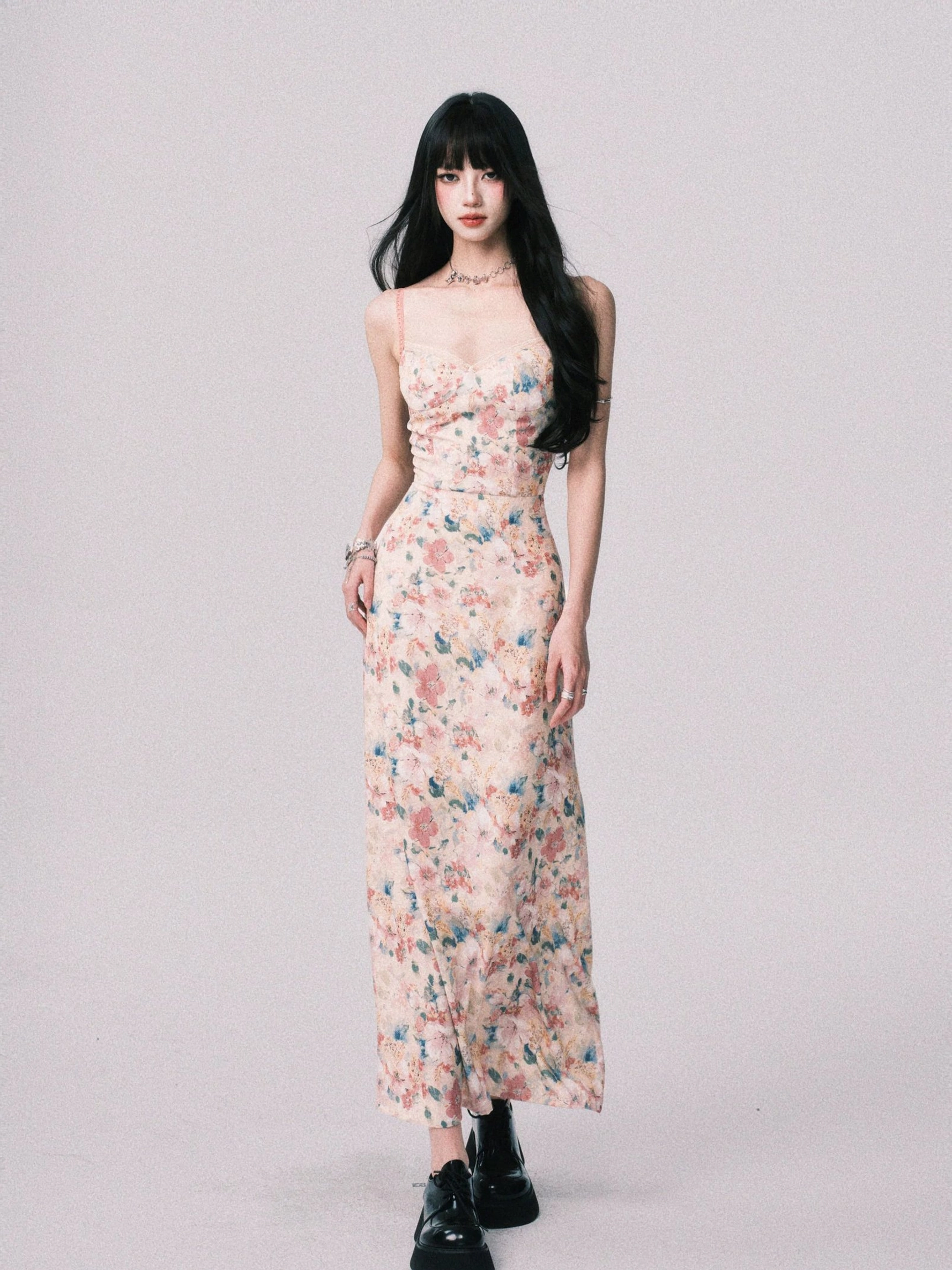 Front full body view of a pink floral maxi dress featuring a low sweetheart neckline, fitted waist, slim cami straps, and watercolor flower print