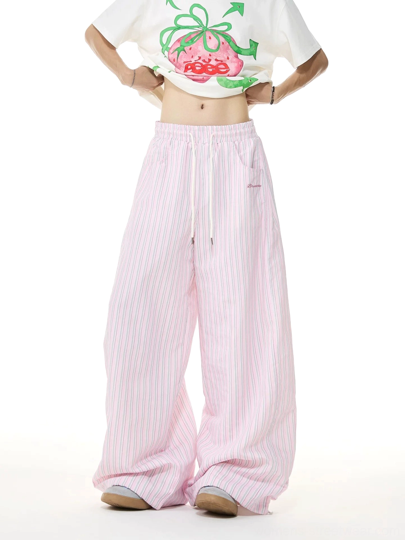 Front view of women's pink and white striped wide-leg streetwear lounge pants with elastic drawstring waist and embroidered waist label styled with a cropped white graphic T-shirt