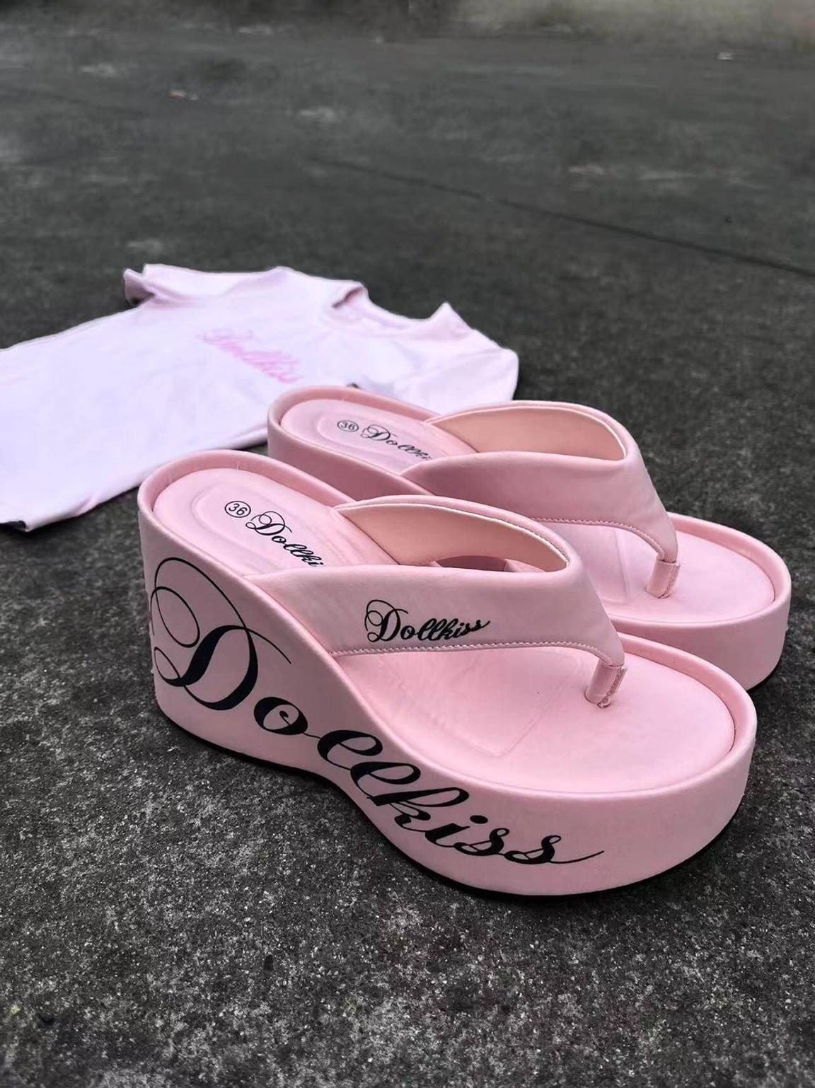 Top view of pink Y2K logo print platform wedge flip-flops styled beside a matching pink graphic t-shirt