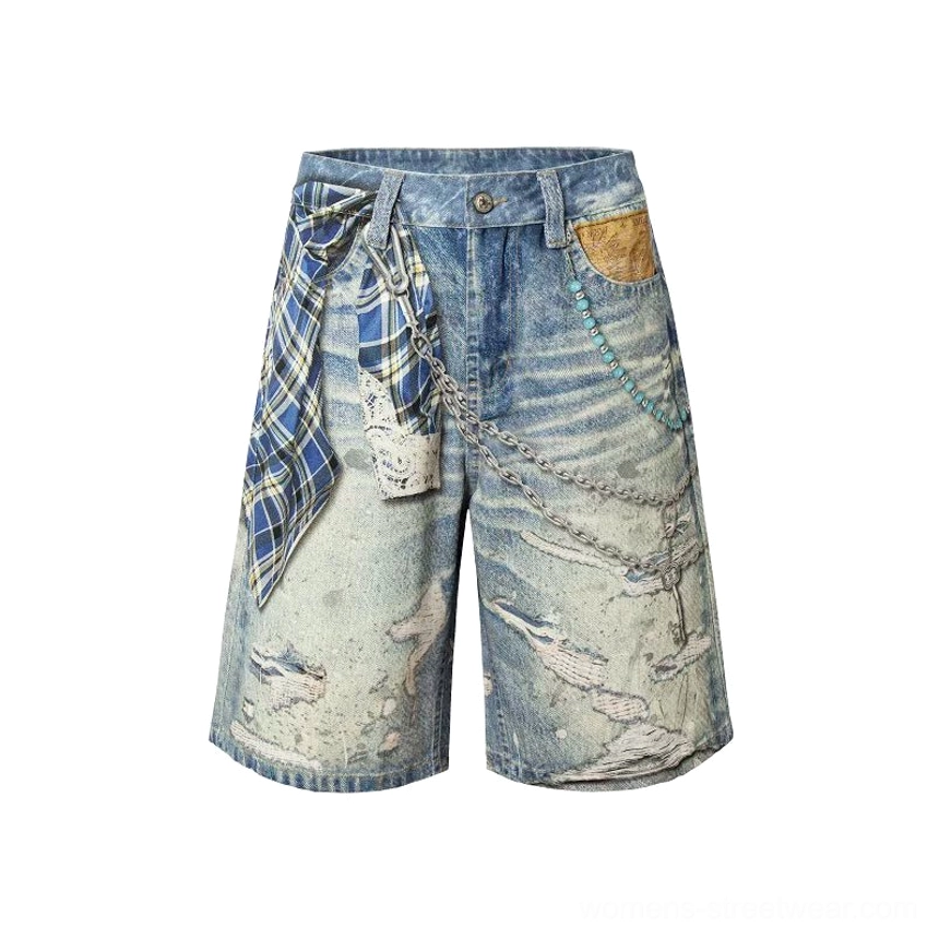 Front studio view of washed blue plaid chain print distressed denim jorts with wide legs, plaid patchwork, decorative chains, beaded trims, and ripped streetwear detailing